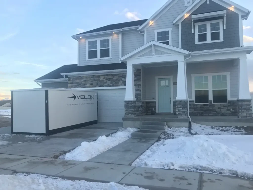 A Velox Mobile Storage container parked in a snowy residential driveway in Utah