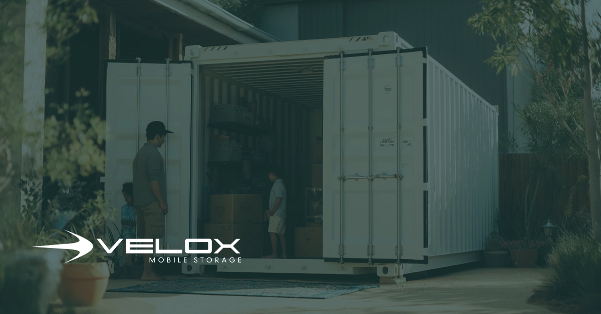 A family stands at the open doors of a white Velox Mobile Storage container parked in a driveway, assessing how to pack their moving boxes and furniture.