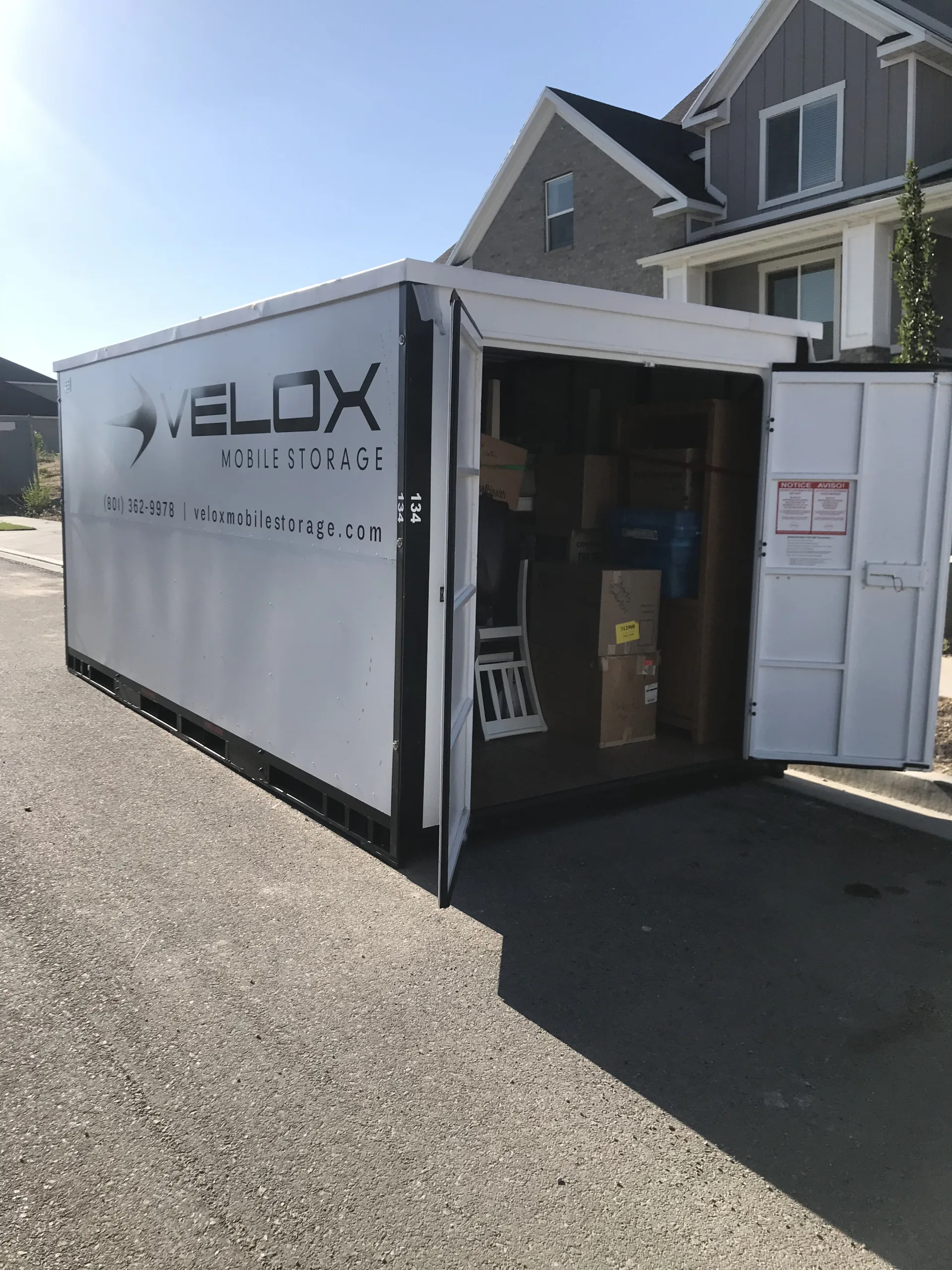 An open Velox Mobile Storage container partly loaded with furniture and boxes