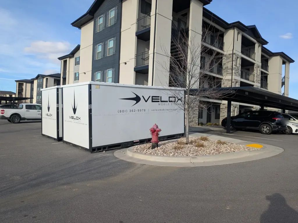 Two Velox portable storage containers in the parking lot of an apartment complex in Orem, Utah
