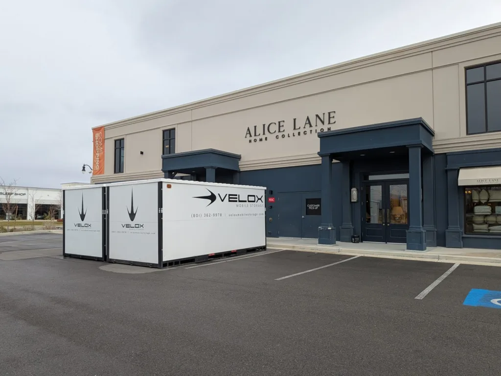 Two white Velox Mobile Storage containers set in a parking lot outside a store in Draper, Utah