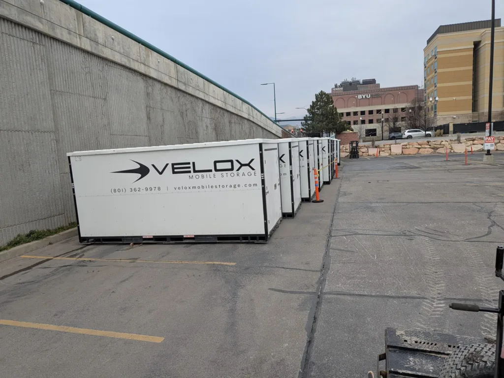 A row of Velox Mobile Storage containers lined up against a wall in a downtown Salt Lake City lot