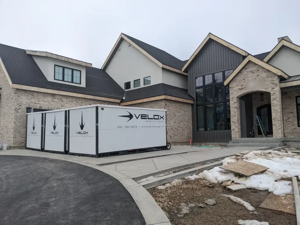 Three Velox portable storage containers lined up at a new brick home in Salem, Utah